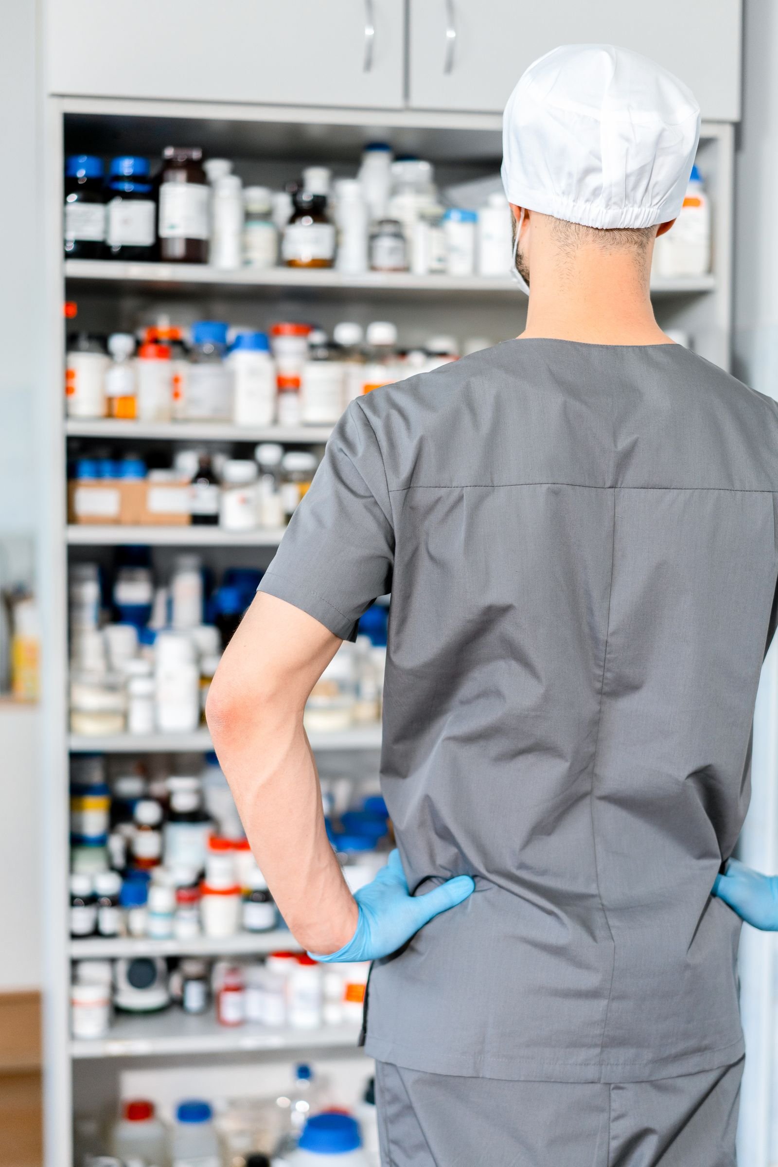Pharmacist organizing shelves of medication in a hospital pharmacy.