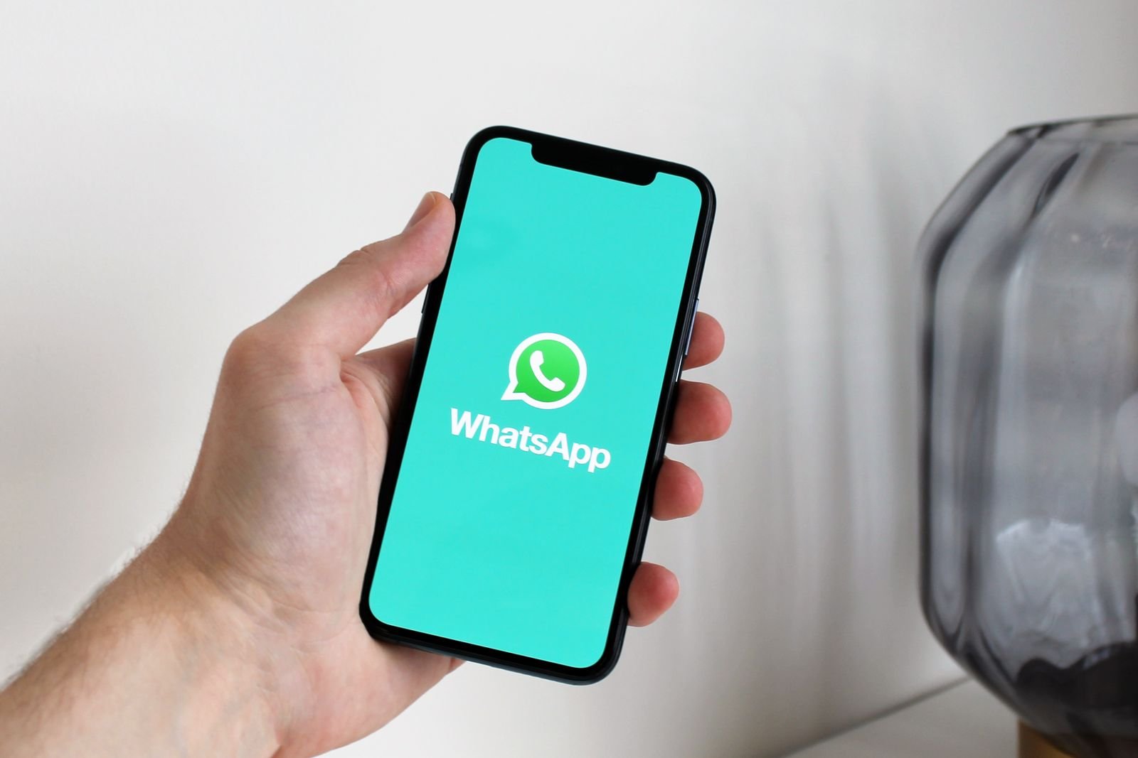 A hand holding a smartphone displaying the WhatsApp app screen.