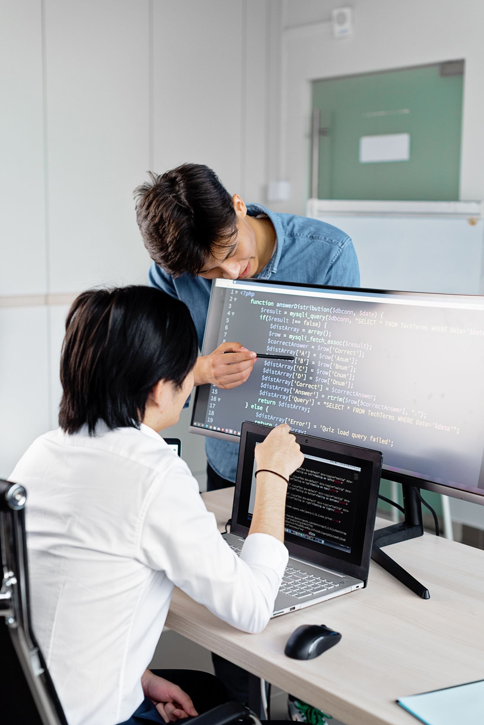 Two developers collaborating around laptops reviewing code.