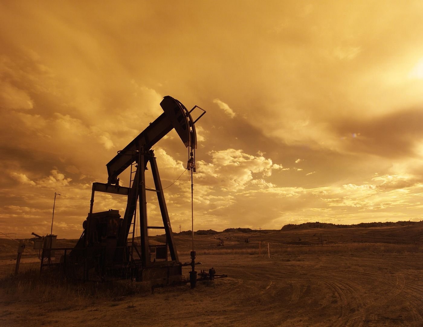 Oil pump-jack silhouetted against a sunset sky.