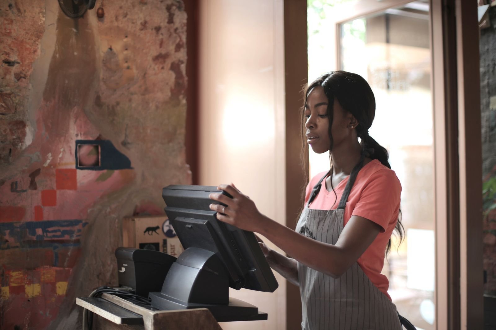 Retail cashier serving a customer at a point-of-sale counter.
